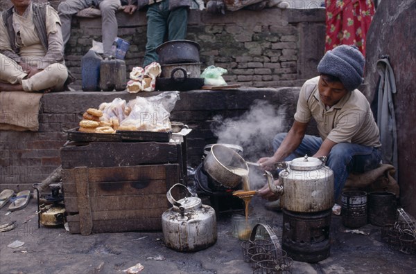 NEPAL, Markets, Food and Drink, Tea-wallah preparing tea boiled with milk and sugar and served in glasses to sell in market.