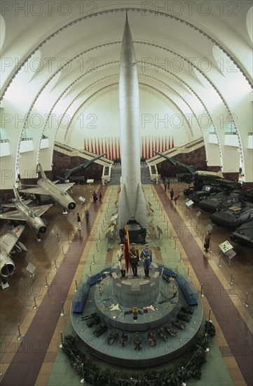 CHINA, Beijing, "Interior hall of the Chinese Military Museum with visitors looking at display of military aircraft, tanks and missiles."