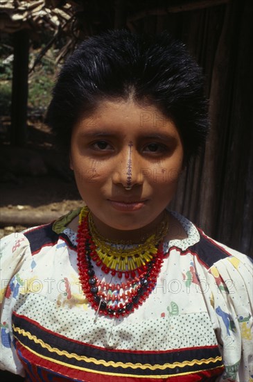 COLOMBIA, Darien, Kuna Indians, Head and shoulders portrait of Kuna girl from the Arquia community wearing small gold nose ring  brightly coloured necklaces and traditional facial decoration including thin painted black line down bridge of nose .  Kuna Cuna American Classic Classical Colombian Colored Columbia Hispanic Historical Latin America Latino Older South America