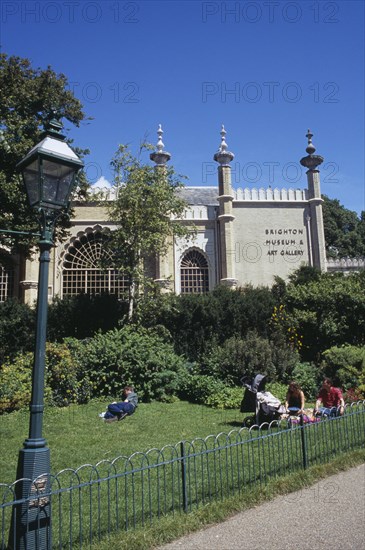 ENGLAND, East Sussex, Brighton, Brighton Museum and Art Gallery seen from The Royal Pavilion gardens with families sitting on the grass