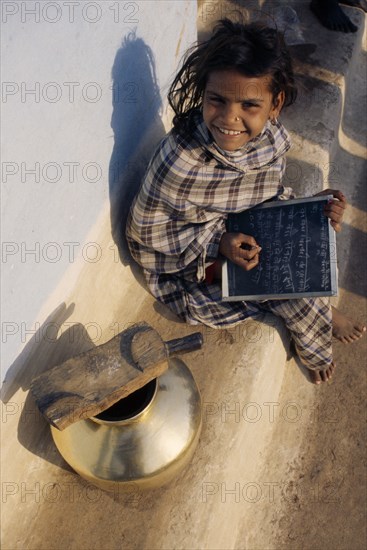 INDIA, Madhya Pradesh, Orccha, Looking down on smiling young girl using chalk to write on slate.