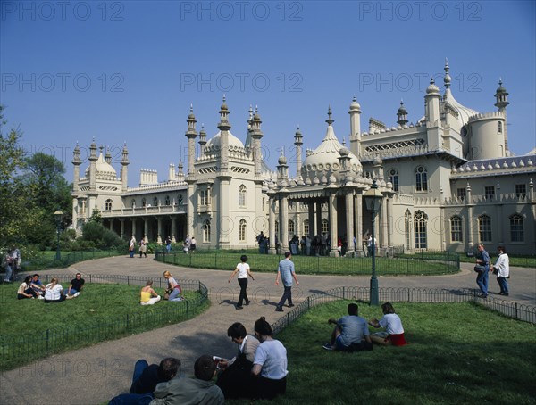 ENGLAND, East Sussex, Brighton, The Royal Pavilion seen from the gardens with visitors at entrance and sitting on the grass