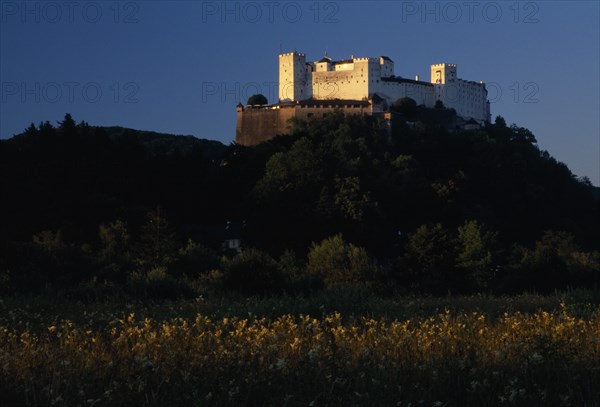 AUSTRIA, Salzburg, Hohensalzburg fortress situated on densely wooded hillside with meadows below.  Construction started 1077 by Archbishop Gebhard.