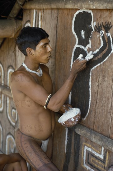COLOMBIA, North West Amazon, Tukano Indigenous People, Cropped shot of Barasana Indian painting spirit guardian on front of maloca  communal home. Tukano sedentary tribe Indian North Western Amazonia maloca American Colombian Columbia Hispanic Indegent Latin America Latino Religion South America Tukano One individual Solo Lone Solitary Religious