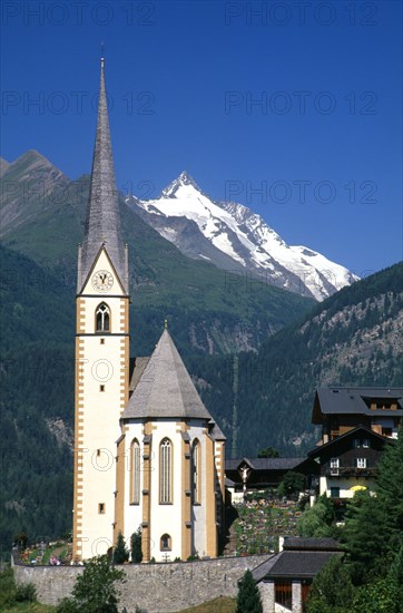 AUSTRIA, Hohe Tauern, Karnten, "High Tauern National Park, Heiligenblut.  Parish church of St Vincent with snow capped Grossglockner peak behind."