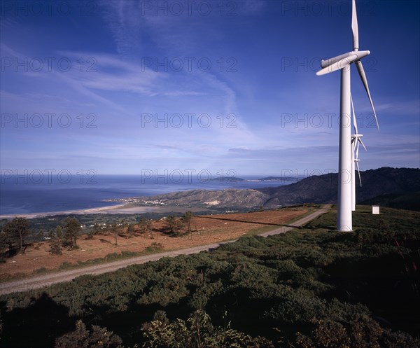 SPAIN, Galicia, Praia de Carnota, Coastal landscape with line of wind powered electricity generators and high windswept clouds.