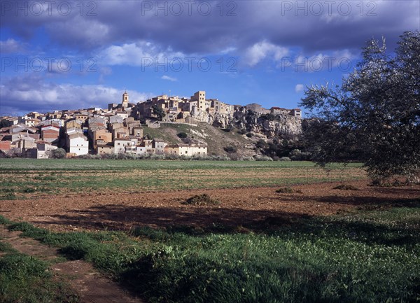 SPAIN, Catalonia, Tarragona, El Pinell de Brai. Hilltop village seen from a field below.