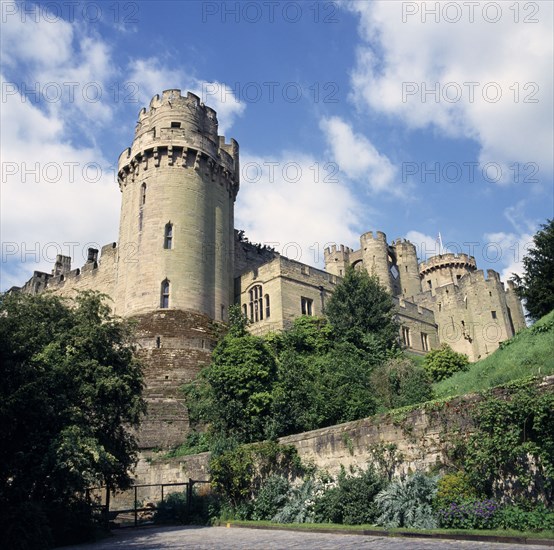ENGLAND, Warwickshire, Warwick, Warwick Castle from Mill Street.  Original castle built by William the Conqueror in 1068 and rebuilt in stone in the 12th c.  Crenellated walls and towers.