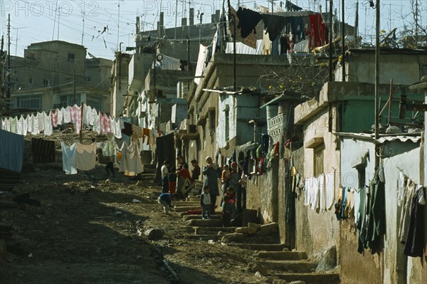 Jordan, Amman, Palestinian refugee camp, women and children outside housing with laundry hanging.