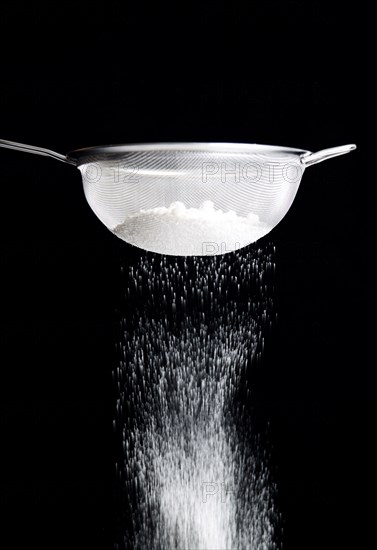 Food, Baking, Flour, White plain flour being siifted through a sieve against a black background.