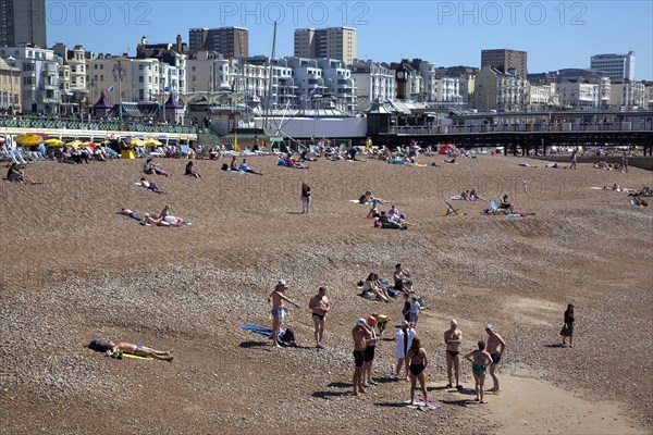 England, East Sussex, Brighton, people sunbathing on the pebble beach.