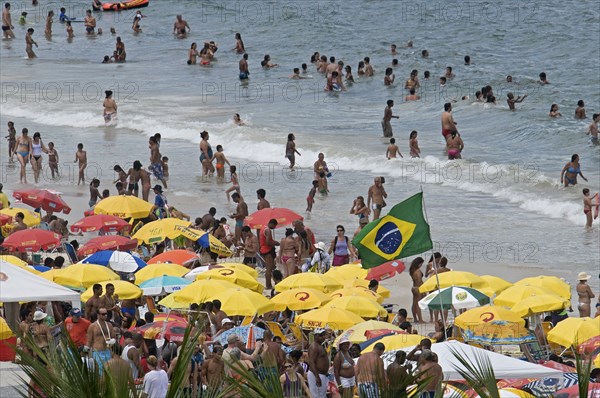 Rio de Janeiro, Brazil. Copacabana beach. Crowds on the beach and in the sea bikinis multi-coloured beach umbrellas and Brazilian flag. Brazil Brasil Brazilian Brasilian South America Latin Latino American City Travel Destination Urban Vacation Beach Beaches People Sunbathing Crowds Rio de Janeiro Copacabana Umbrellas Parasols Destination Destinations Holidaymakers Latin America Sand Sandy Beach Tourism Seaside Shore Tourist Tourists Vacation Sand Sandy Beaches Tourism Seaside Shore Tourist Tourists Vacation South America Southern Sunbather Water