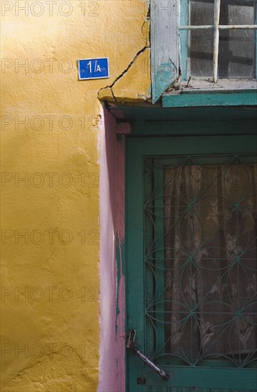 Kusadasi, Aydin Province, Turkey. Detail of exterior facade of house in the old town numbered 1A. With yellow and pink painted walls and turquoise painted door and window frames. Turkey Turkish Eurasia Eurasian Europe Asia Turkiye Aydin Province Kusadasi Door Wall Window Color Colour Colorful Colourful Multi Colored Coloured Destination Destinations European Middle East South Eastern Europe Western Asia