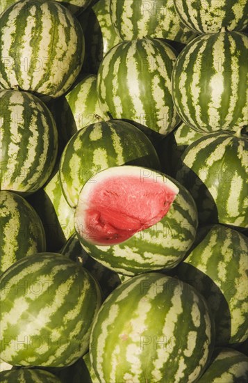 Kusadasi, Aydin Province, Turkey. Fresh watermelon on sale at town produce market with fruit at centre cut open to reveal red flesh and seeds. Turkey Turkish Eurasia Eurasian Europe Asia Turkiye Aydin Province Kusadasi Market Fruit Display Melon Watermelon Water Melons Watermelons Green Yello Red Pattern Center Color Destination Destinations European Middle East South Eastern Europe Western Asia