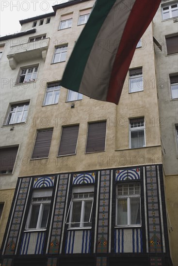 Budapest, Pest County, Hungary. Part view of Art Nouveau facade with flag in top foreground. Hungary Hungarian Europe European Budapest Buda Pest Art Nouveau Facade Architecture Flag Front Frontage Destination Destinations Eastern Europe