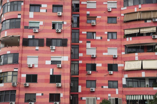 Albania, Tirane, Tirana, Part view of exterior facade of colourful apartment building with shuttered windows and air conditioning units.