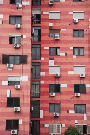 Albania, Tirane, Tirana, Part view of exterior facade of colourful apartment building with shuttered windows and air conditioning units.