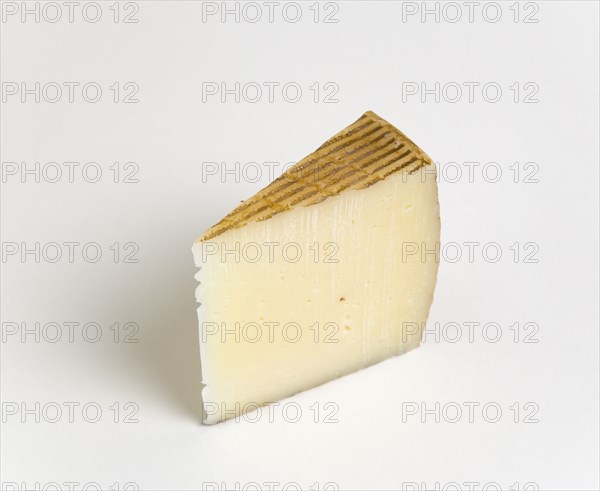 Slice of Spanish Manchego cheese made from pasteurised Manchega sheeps milk from the La Mancha region of Spain against a white background. Photo: Paul Seheult